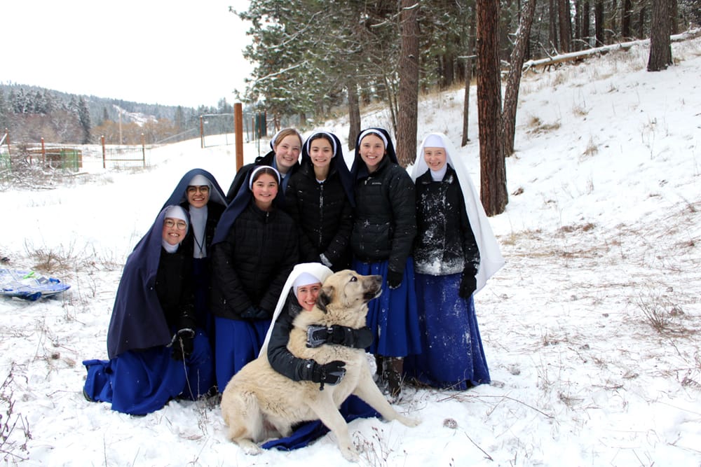 Youngsters of all ages need to play in the snow. The novitiate dog, however, rebels once again over having to be included in the picture.