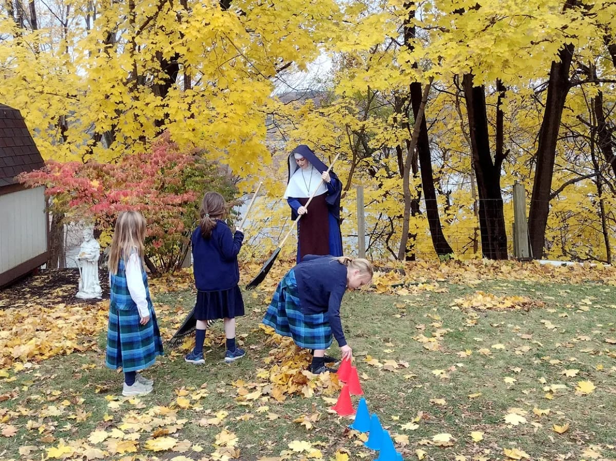 Sr. Maria Dolorosa and her students help tidy up the grounds at Holy Rosary Church in Middleville, Michigan.