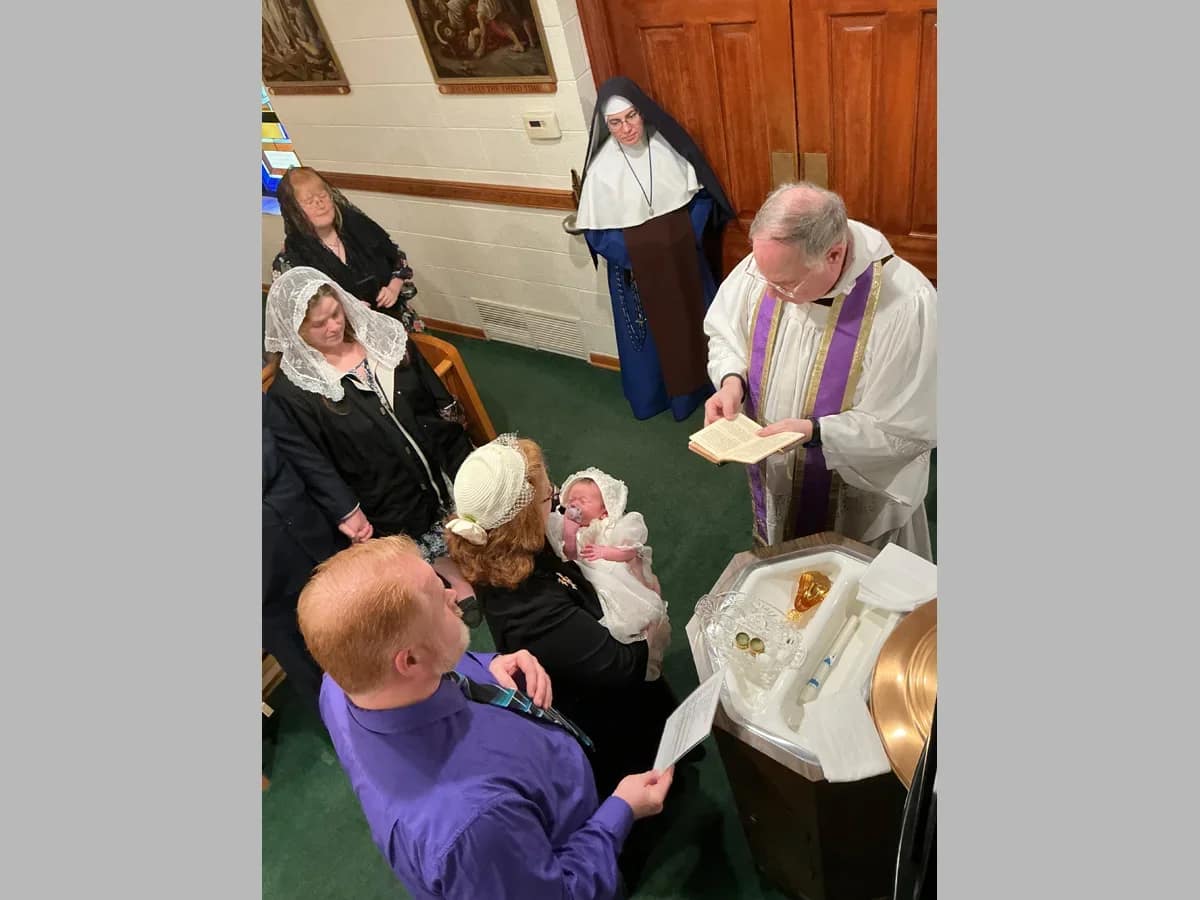 Sr. Bernardine Marie looks on while Father Francisco Radecki baptizes a tiny new parishioner of St. Joseph’s Church inWayne, Michigan.