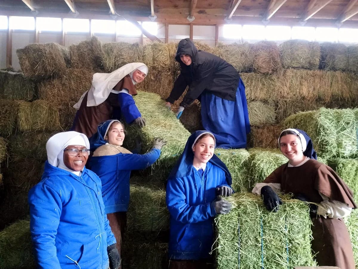 Postulants and novices pose for a photo while loading in hay for the winter.