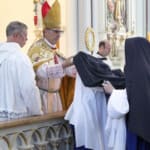 After making their first profession of simple vows, the four white-veiled novices receive the blue veils of the professed.