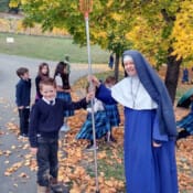 Sr. Mary Imelda works to get a ball out of the culvert with the help of a little boy and a long pole (Rathdrum, Idaho) Sister and students on a fall day