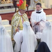 After having had their hair cut by the Bishop, our four postulants, in simple white dresses, receive their white novice veils.
