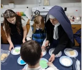 Sr. Mary Angela helps students at St. Philomena Academy, Middleville, Michigan to frost cookies of their State.