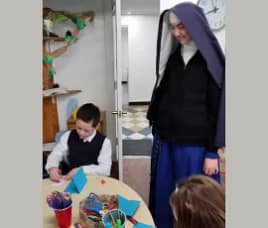 Sr. Maria Goretti looks on as students make feast- day cards for Fr. Gabriel Lavery.