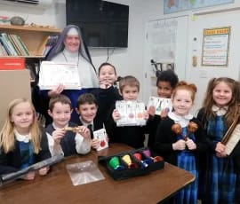 Sr. Mary Genevieve and her students pose as a “Thank You” photo for the Sister who sent these bells and other musical instruments.