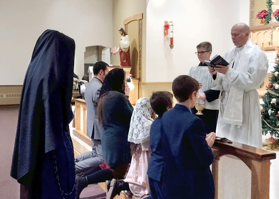 Fr. Letourneau enrolls a new family in the Brown Scapular at St. Theresa’s Church in Oakland, Maine. Two of the children received their First Holy Communion on Christmas Day.