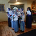 Sr. Mary Genevieve joins the sodalists at Mary Immaculate Queen parish in presenting May flowers to Our Lady Sister and sodalists at the City of Mary