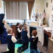 Kneeling at their classroom’s altar replica, Sr. Mary Josephine leads her kindergarteners in a prayer (Rathdrum, Idaho). Sister and kindergarteners kneel at the class altar.